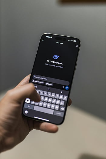 hand holding smartphone, AI chat application, DeepSeek interface, modern technology, smartphone display, AI chatbot, DeepSeek chat, digital communication, mobile technology, user interface, smart device