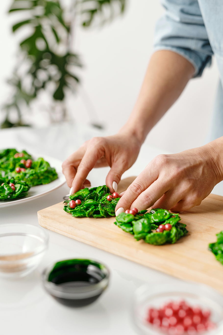 fresh vegetable salad, wooden tray, holiday-themed food, green wreaths, red berries, food preparation, creative cooking, festive meal, healthy eating, seasonal dish, person preparing food