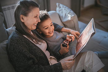 mother and son, reading book, children's book, bonding moment, home setting, shared smiles, happy family, child holding toy, cozy atmosphere, family time, indoor scene