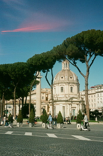 Rome, Italy, Roman dome, historic architecture, tall Pini trees, cityscape, urban view, cobblestone street, scooter riders, blue sky, pink cloud