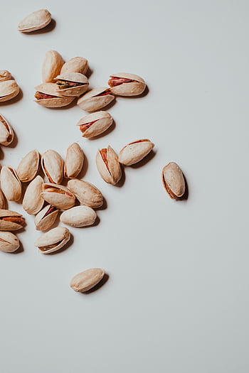 pistachio nuts, pistachios in shells, organic pistachios, light surface, top view, scattered pistachios, pistachio shells, healthy snacks, nutty texture, pistachio close-up, pistachio photography