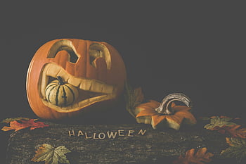 jack-o'-lantern, brown wooden surface, carved pumpkin, gourd, autumn leaves, Halloween decor, Halloween, fall decoration, seasonal decor, carved face, festive display