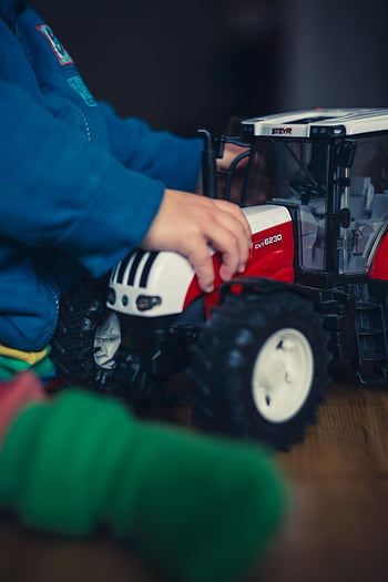 bermain anak, jaket biru, mainan traktor merah, permainan imajinatif, bermain di dalam ruangan, traktor mainan, anak kecil, mainan dalam ruangan, traktor merah dan putih, mainan anak, kegiatan dalam ruangan