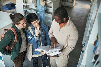Studenti v knihovně, rozmanité studenti, spolupráce na knize, Nastavení knihovny, skupina studentů, Studium společně, vzdělávací prostředí, diskuse o knize, Akademická spolupráce, knihovna Knihovna, učit se společně