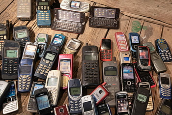 vanhentuneet puhelimet, retro-matkapuhelimet, pino puhelimia, nostalginen tekniikka, maalaismainen puinen pinta, Vintage -matkapuhelimet, Nokia-puhelimet, valikoituja puhelimia, vanhat matkapuhelimet, matkapuhelinkokoelma, nostalgisia vempaimia