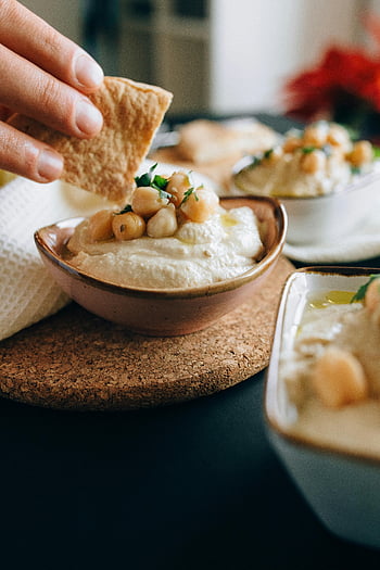 pita bread, creamy hummus, chickpeas, brown ceramic bowl, close-up, dipping, hand, food photography, appetizer, middle eastern cuisine, healthy eating