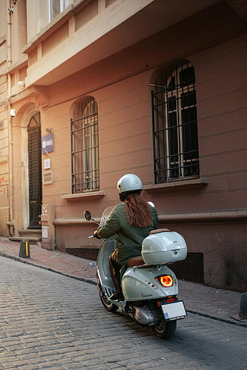 woman riding scooter, Istanbul cobblestone street, urban lifestyle, motor scooter, woman on scooter, city street, scooter rider, helmet, Vespa, Turkish street, urban scene