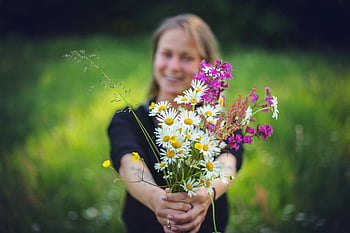 woman holding flowers, colorful bouquet, wildflowers, smiling woman, outdoors, blurred green background, nature photography, floral bouquet, natural setting, spring flowers, daisies
