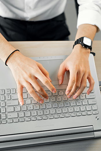 high angle shot, person typing, laptop keyboard, close-up hands, above view, wristwatch, business attire, office setting, desk work, computer use, productivity