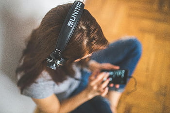 Donna con cuffie, ascoltare la musica, vista dall'alto, smartphone, cuffie, Unitra, Abbigliamento casual, impostazione interna, postura rilassata, pavimento di legno, divertimento musicale