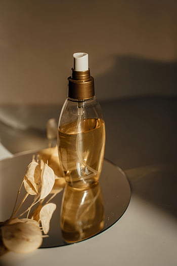 Klar glas kosmetisk flaske, massageolie, æstetisk glasflaske, tørrede blomster, varmt lys, spejlrefleksion, nærbillede skudt, skønhedsprodukt, Spa æstetisk, gylden væske, dekorative flaske