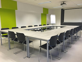 konferenční místnost, Stůl ve tvaru U., černé židle, bílý stůl, moderní nastavení, světlý pokoj, prostor pro setkání, Prezentační oblast, zelené zdi, kancelářský nábytek, prostředí