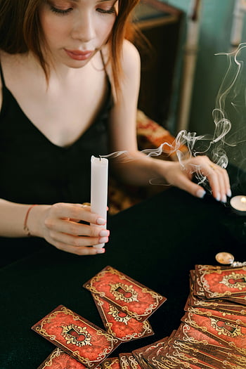 vrouw in zwarte tanktop, kaarsenhouder vasthouden, tarotkaarten lezen, mystieke aura, tarot lezen, kaars rook, spirituele oefening, waarzeggerij, esoterisch ritueel, waarzeggen, mystieke scène