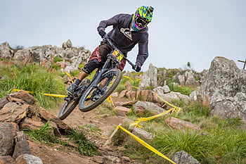 man with green helmet, riding bicycle, rocky downhill trail, extreme mountain biking, cyclist skills, outdoor adventure, mountain biking, rocky terrain, downhill biking, extreme sports, outdoor activity