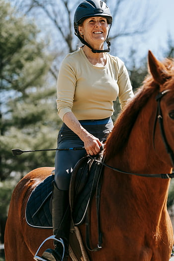 žena jezdecký kůň, Jezdecký životní styl, Slunečná jízda, portrét ženy, jízda na koni, venkovní aktivita, jezdecký sport, usmívající se žena, jezdecké vybavení, helma