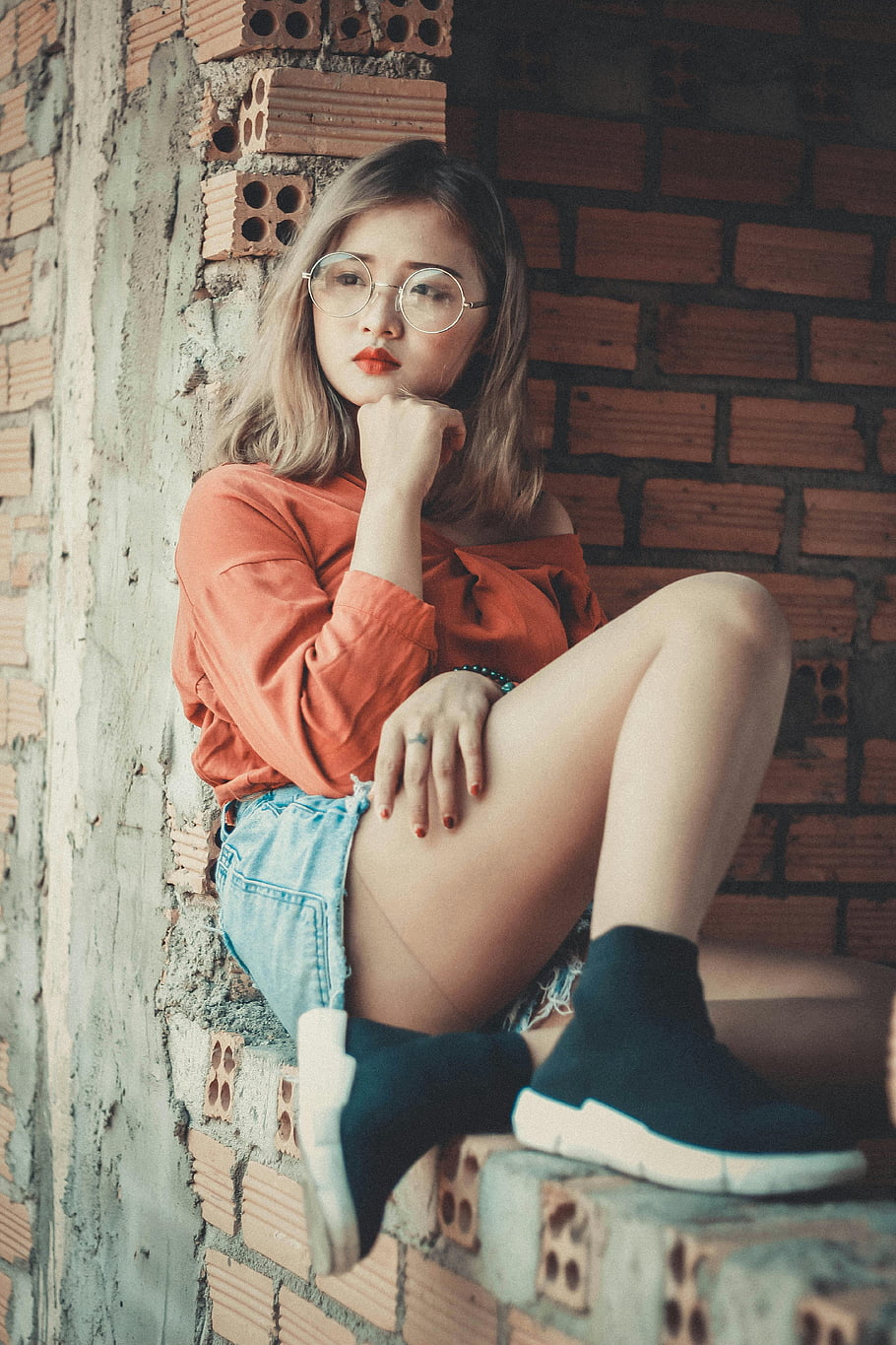 top s kulatým výstřihem, Modré džínoviny, Stylová mladá žena, ležérní trendy outfit, brýle, Vnitřní pozice, cihlová zeď pozadí, módní fotografie, trendy móda, Ležérní styl, Vnitřní módní střílení