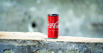 Coca-Cola can, brown concrete surface, rough concrete, blurred background, Coca-Cola, can, concrete, outdoor setting, soft drink, beverage, soda