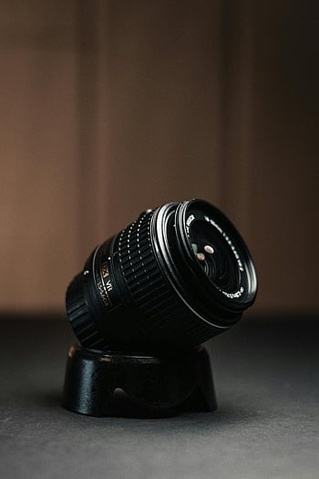 objektiv fotoaparátu dslr, černý objektiv fotoaparátu, Design objektivu fotoaparátu, Mechanika objektivu fotoaparátu, Close-up kamera čočka, hnědý dřevěný stůl, stojan na čočky kamery, fotografické vybavení, příslušenství fotoaparátu, detaily objektivu, technologie kamer