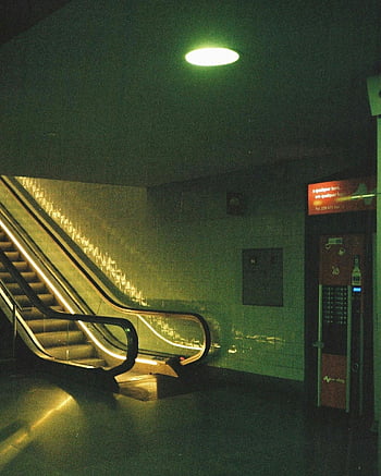Porton metroasema, himmeästi valaistu liukuportaat, salaperäinen tunnelma, elokuvamainen tunnelma, maanalainen kuljetus, julkinen liikenne, kaupunkien infrastruktuuria, liukuportaat metrossa, metroaseman sisätilat, vihreä valaistus, yökuvaus
