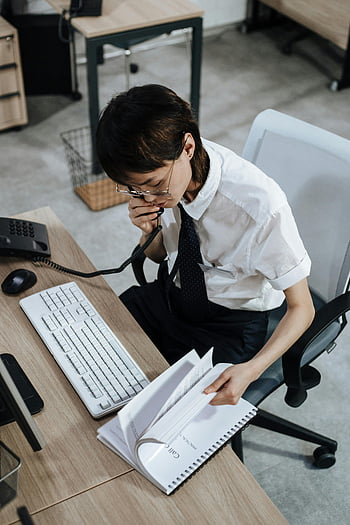 働く女性、 事務机、 電話、 書類、 効率的なタスク、 オフィス環境、 ビジネススーツ、 キーボード、 事務用椅子、 プロの環境、 ワークスペース