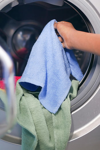 laundry, washing machine, colorful towels, front-loading, hand, close-up, doing laundry, household chores, cleaning, laundry day, towels