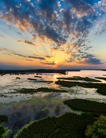 drone shot, wetland, sunset, Randolph MN, vibrant skies, tranquil waters, serene landscape, aerial view, natural scenery, lush wetlands, peaceful environment