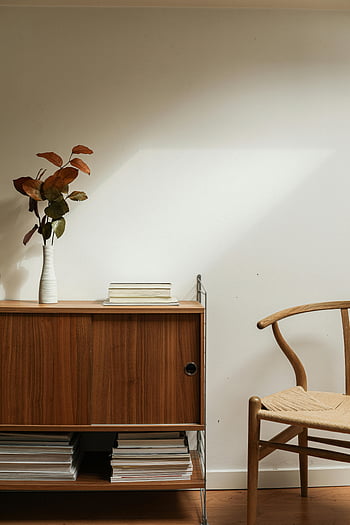 brązowe drewniane krzesło, brązowa drewniana szafka, minimalistyczne wnętrze, Drewniany kredens, ceramiczny wazon, spokojny projekt, projektowanie wnętrz, nowoczesne meble, wystrój domu, salon, książki