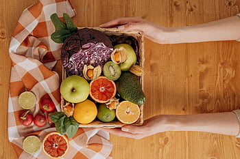 basket of fruits, fresh fruits, wooden table, hands holding, vibrant basket, fresh vegetables, checkered cloth, healthy eating, fruit basket, fresh produce, person holding basket