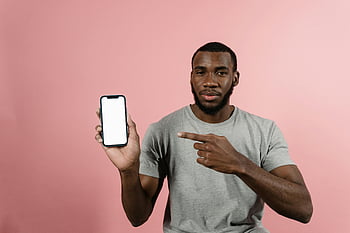 Muž v šedé košili, držení smartphone, ukazující na obrazovku, dospělého muže, Šedá košile, smartphone obrazovky, směřující gesto, Růžové pozadí, ležérní oblečení, využití technologie