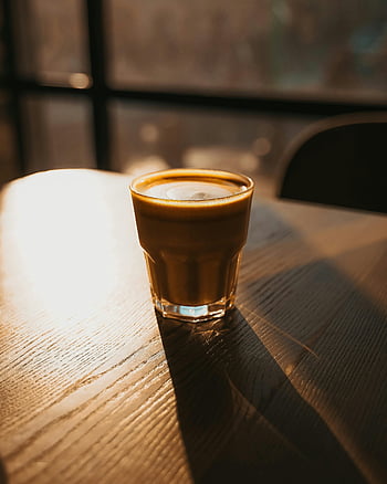 coffee, cappuccino, close-up, wooden table, sunset light, cozy, relaxation, warm light, glass cup, indoor setting, beverage