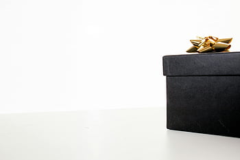 černá dárková krabička, zlatá stuha, bílé pozadí, minimalistický design, oslavy, Elegantní balení, luxusní dárek, jednoduchá elegance, Slavnostní prezentace, moderní styl, Balení dárků