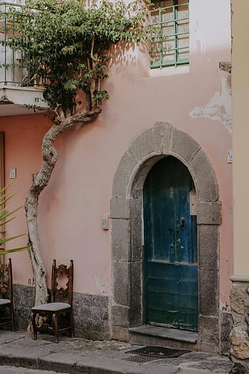 blue wooden door, pink plaster wall, rustic door, ivy, wooden chairs, elegant door, arched doorway, outdoor scene, building entrance, charming doorway, vintage door