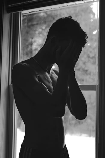 monochrome photo, man showing sadness, silhouette, shirtless man, deep emotion, window, black and white, emotional expression, male figure, indoor scene, contemplative mood