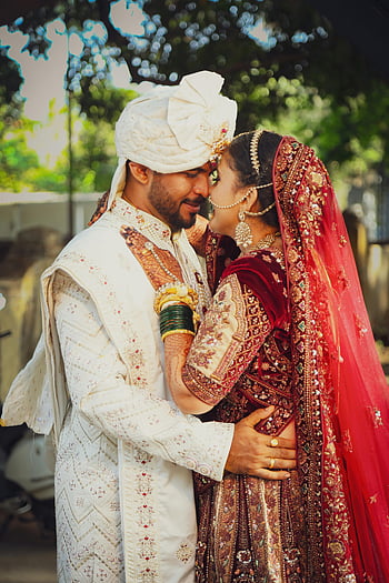 hintli düğün, geleneksel kıyafet, gelin ve damat, açık hava kutlaması, hintli çift, Kırmızı Lehenga, beyaz şervani, türban, takı, kültürel düğün, kucaklamak