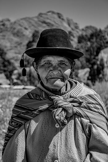 elderly woman, traditional attire, rural landscape, Puno Peru, black and white photo, hat, cultural clothing, Andean woman, indigenous attire, mountain background, traditional hat