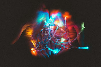 colorful string lights, hands holding lights, vibrant lighting, magical atmosphere, assorted-color lights, glowing lights, festive lights, decorative lights, hand-held lights, string lights, colorful glow