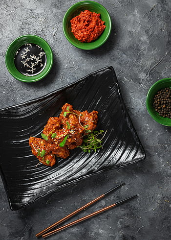 Szkliste smażone mięso, czarna płyta, Pikantny koreański kurczak, sos sojowy, gochujang, fani jedzenia, pyszne danie, kuchnia koreańska, Czarne pałeczki, zielone miski, ziarenka sezamu