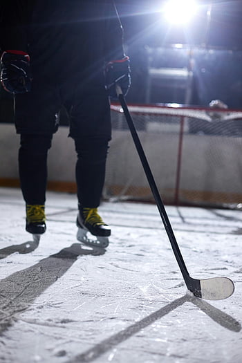 ice hockey player, hockey stick, close-up shot, ice rink, night practice, hockey gear, ice skates, sports equipment, outdoor rink, winter sports, hockey practice