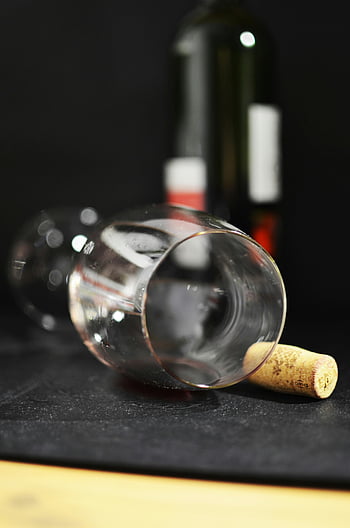wine glass, black surface, empty wine glass, cork, dark background, artistic composition, wine bottle, clear glass, still life, minimalistic, elegant