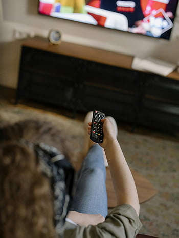 wanita santai, sofa, rumah yang nyaman, menonton televisi, remote control, remote hitam dan perak, ruang keluarga, televisi, remote di tangan, Pengaturan dalam ruangan, pakaian kasual