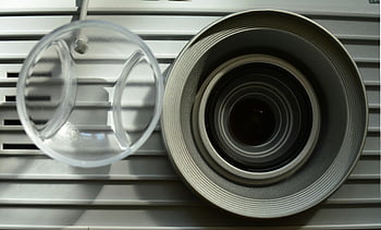 Gray Camera Lens, modern projector lens, metallic elements, detailed close-up, reflections, projector lens, camera lens, metallic reflections, close-up photography, modern projector, detailed lens