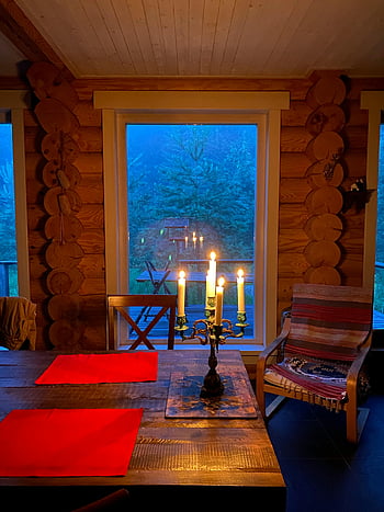 candles, candle holder, wooden table, rustic cabin, forest view, warm candlelight, interior, cabin decor, candlelit dinner, cozy atmosphere, log cabin
