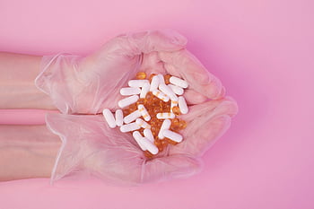pharmaciste des cultures, des pilules, studio rose, prise de vue en studio, mains dans les gants, pilules blanches, pilules jaunes, fond rose, médicaments, des médicaments, soins de santé