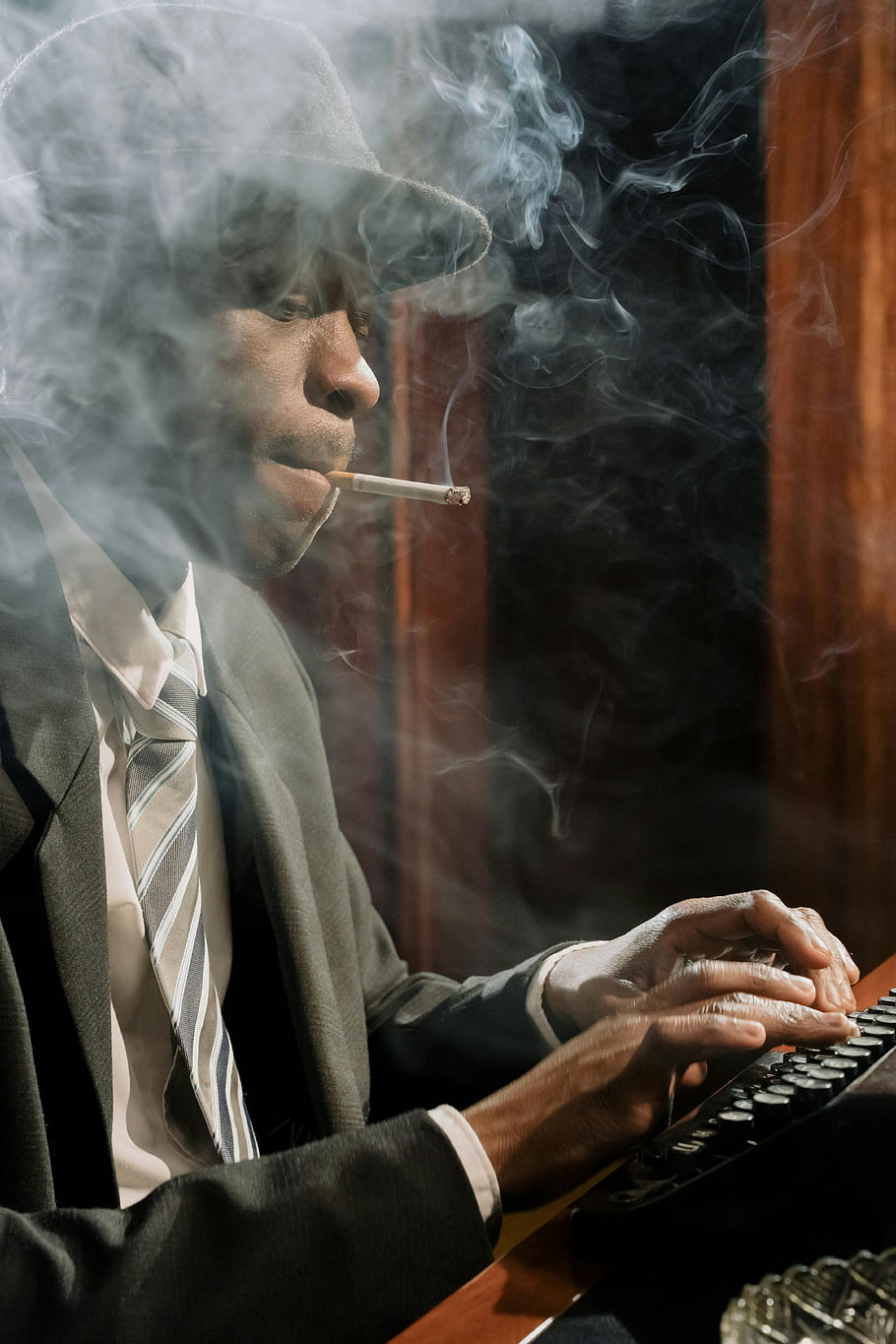detective smoking, vintage typewriter, smoking while working, cinematic noir, moody ambiance, mysterious scene, man in suit, typewriter scene, smoke filled, retro detective, dark background