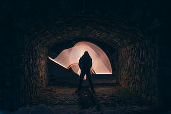 silhouette of a man, light painting art, moody stone tunnel, dark silhouette, light painting, stone tunnel, moody atmosphere, artistic photography, night photography, long exposure, tunnel art