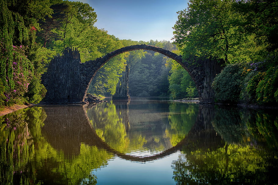 rakotzbrücke, Germania, ponte grigio, alberi, acque calme, vegetazione lussureggiante, riflessione, ponte iconico, bellezza naturale, paesaggio sereno, il ponte del diavolo