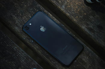 black iPhone 7, smartphone, weathered wooden surface, low light, black phone, iPhone, wooden table, mobile device, technology, dark background, Apple product
