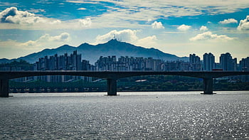 grey concrete bridge, urban skyline, bridge over water, mountains background, daytime cityscape, river bridge, city bridge, mountain view, urban landscape, concrete bridge, city mountains