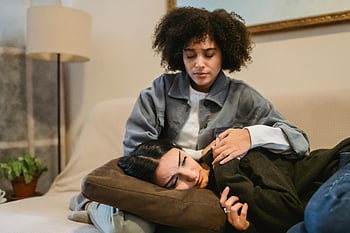 young black woman, cuddling, crying female friend, lying on sofa, comforting embrace, living room, support, friendship, two women, emotional support, sofa