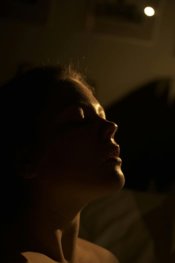 serene portrait, closed eyes, soft lighting, shadowed, young woman, dark room, sensual lady, intimate mood, peaceful expression, artistic lighting, low light photography